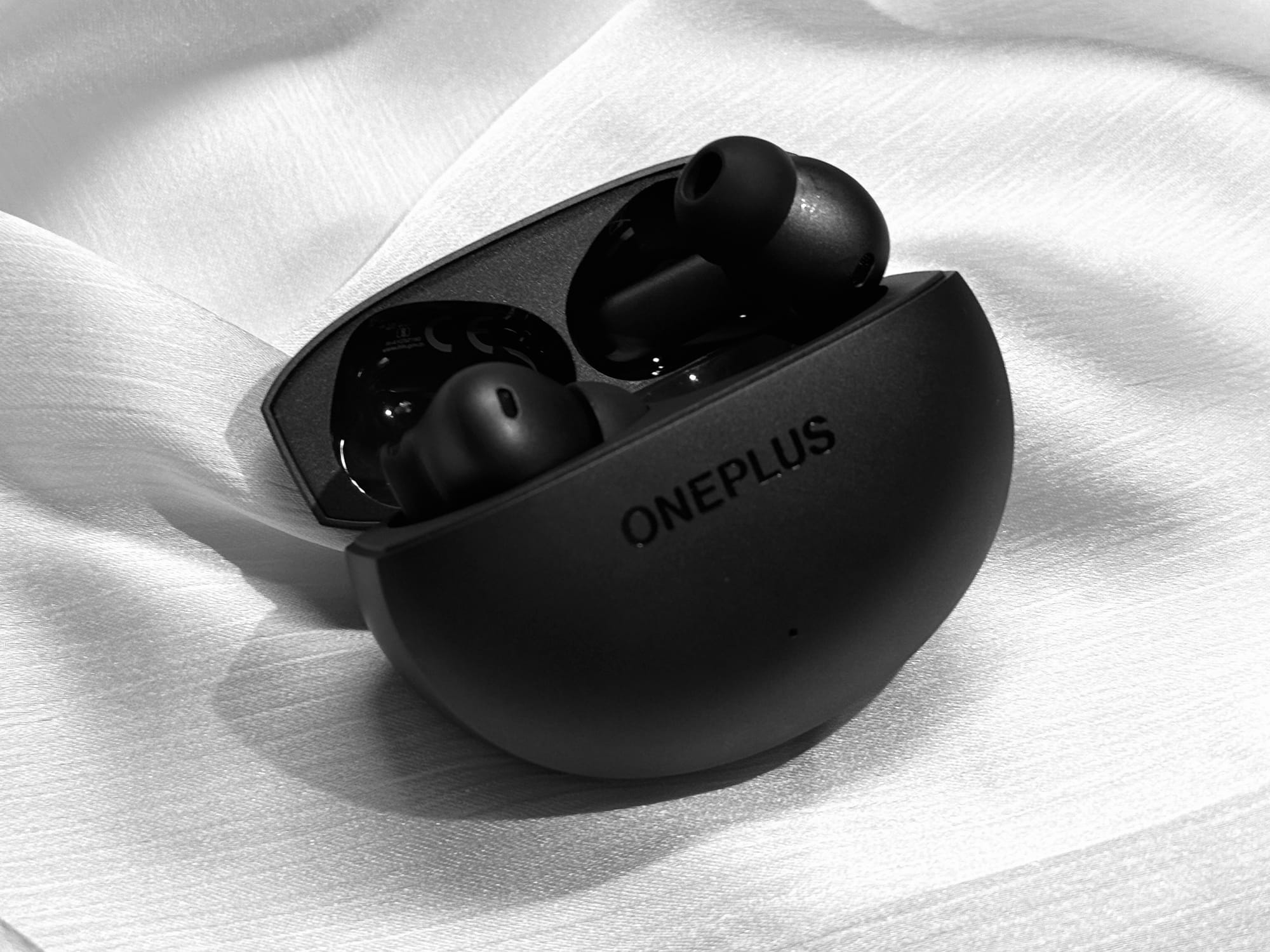 OnePlus Buds 4 earbuds lying on a table in black color.