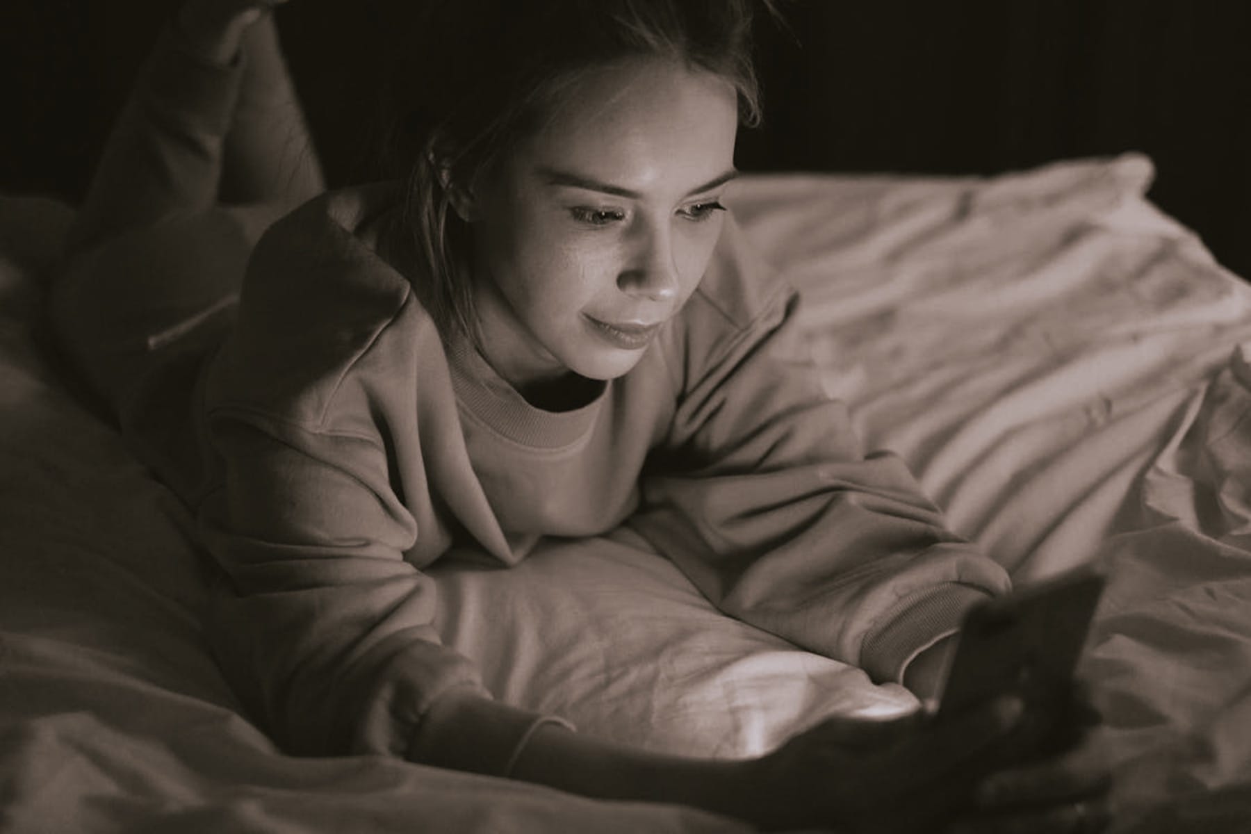 Woman using a phone in bed.