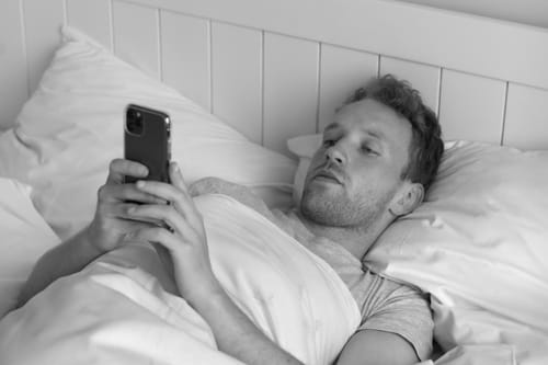 Man using a phone in bed.