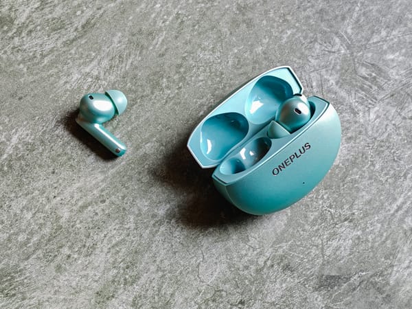OnePlus Buds 4 earbuds lying on a table in green color.